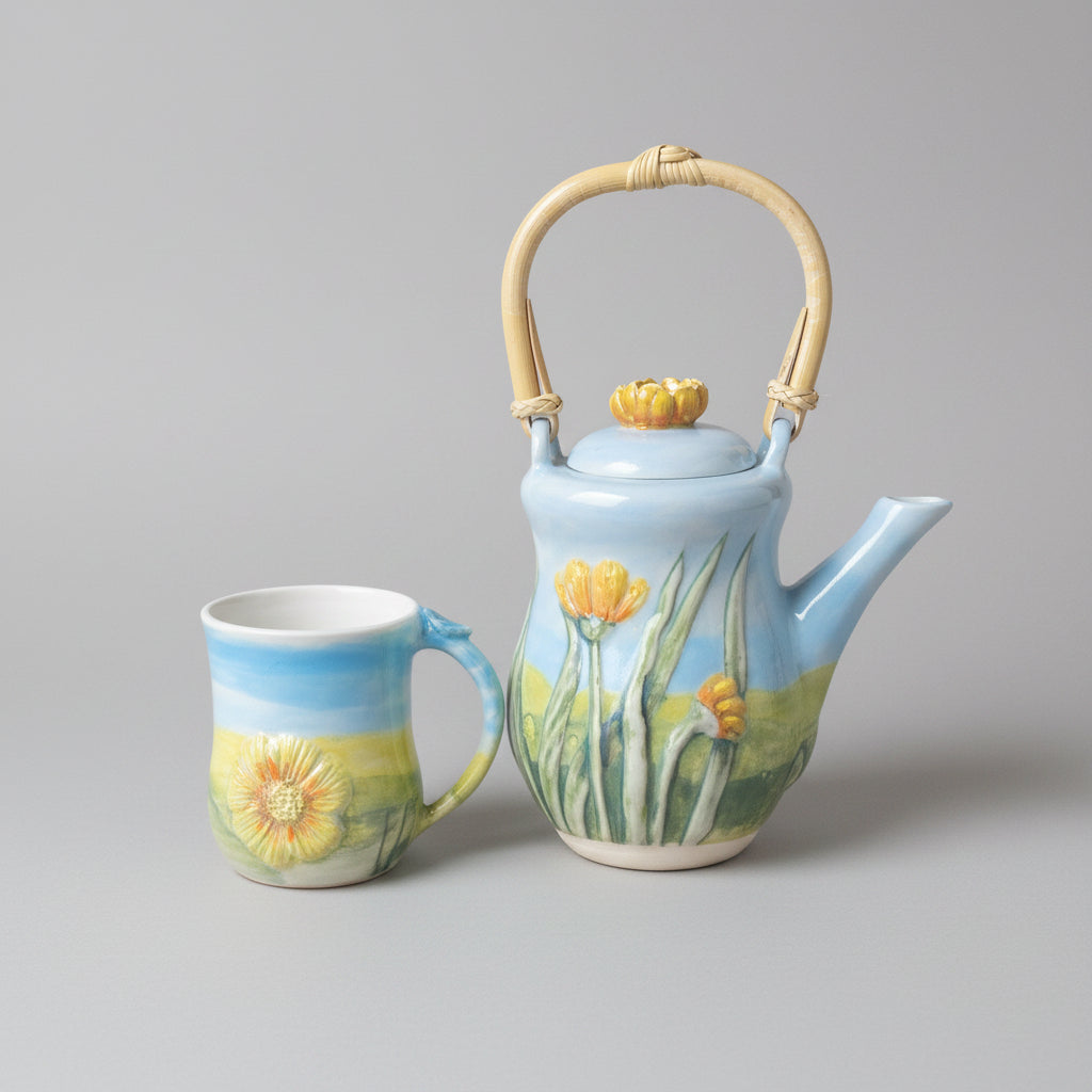 Ceramic teapot and mug with floral design on a background of fields of England