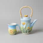 Ceramic teapot and mug with floral design on a background of fields of England